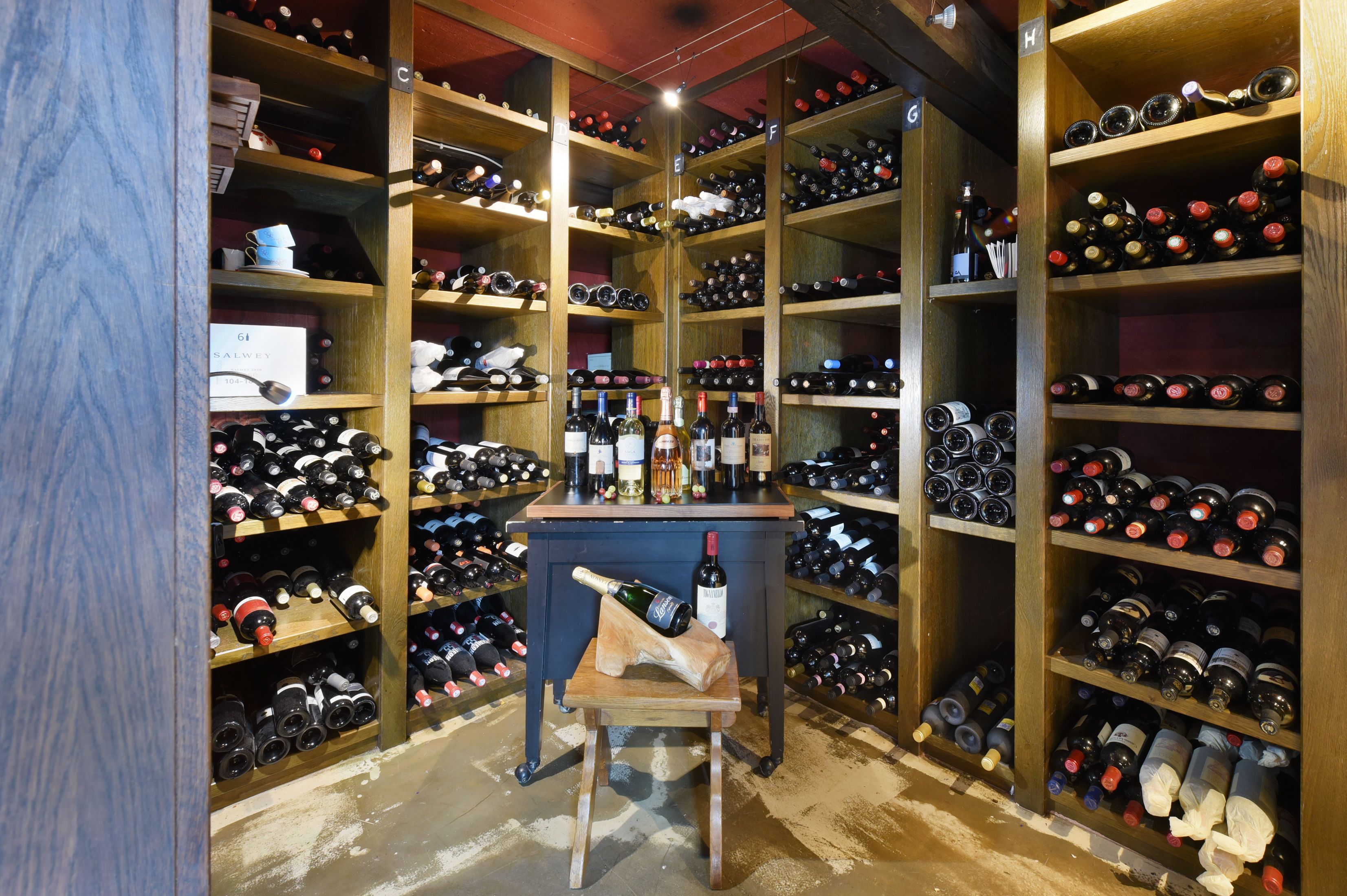 A wine cellar with numerous wine bottles organized on wooden shelves.