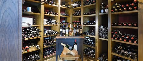 A wine cellar with numerous wine bottles organized on wooden shelves.