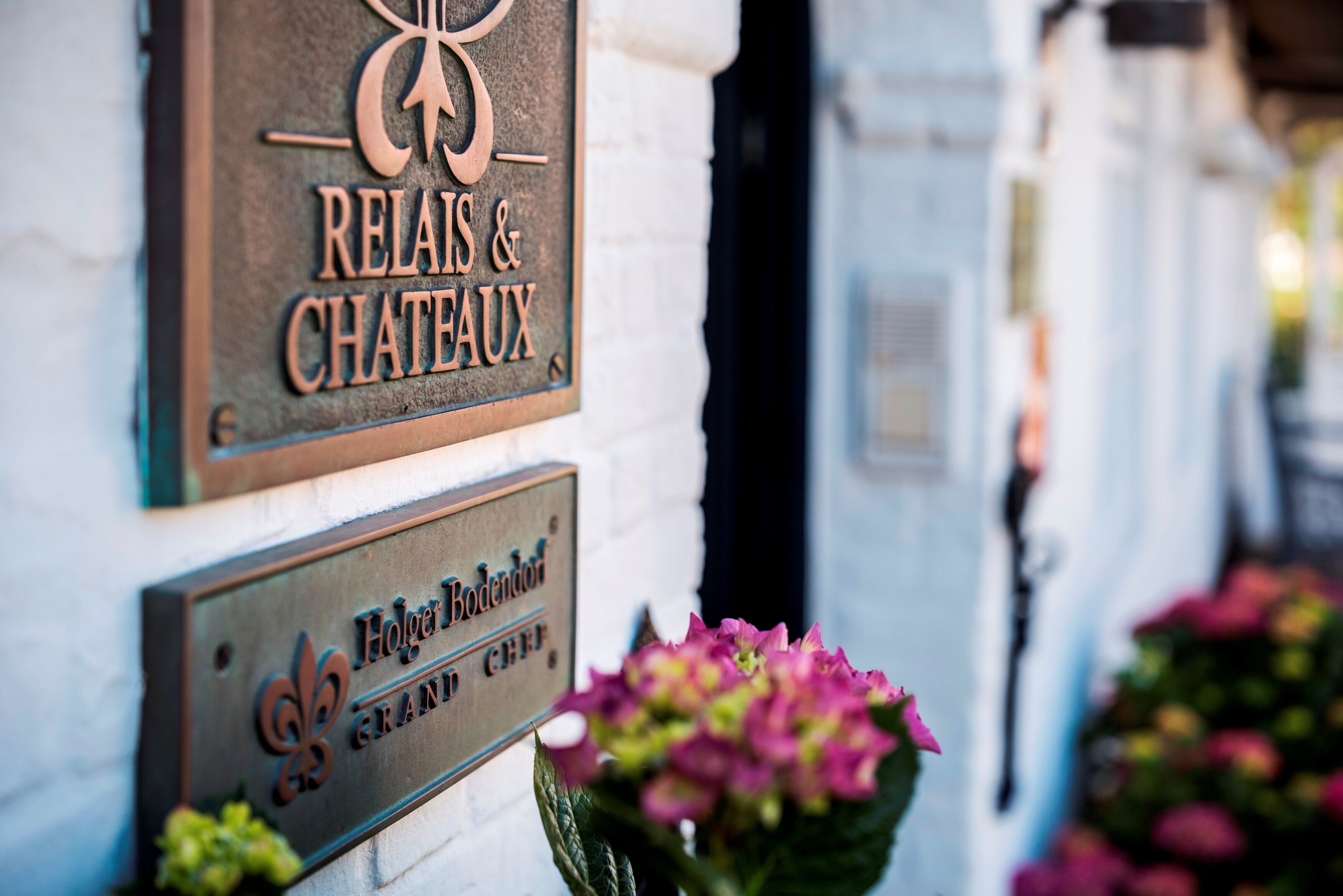 Een bord met 'Relais & Chateaux' en 'Hotel Bodendorfer Grand Hôtel', met een toekanmotief.