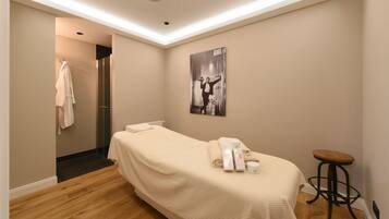 Ein Hotelzimmer mit einem Bett, einem kleinen Hocker, einem Handtuchhalter und einem Bild an der Wand.