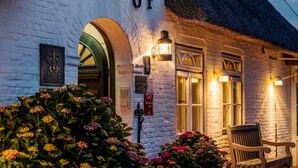 A white brick building with the number 84, a thatched roof, and a bench outside. - Relais & Châteaux Landhaus Stricker (Sylt)