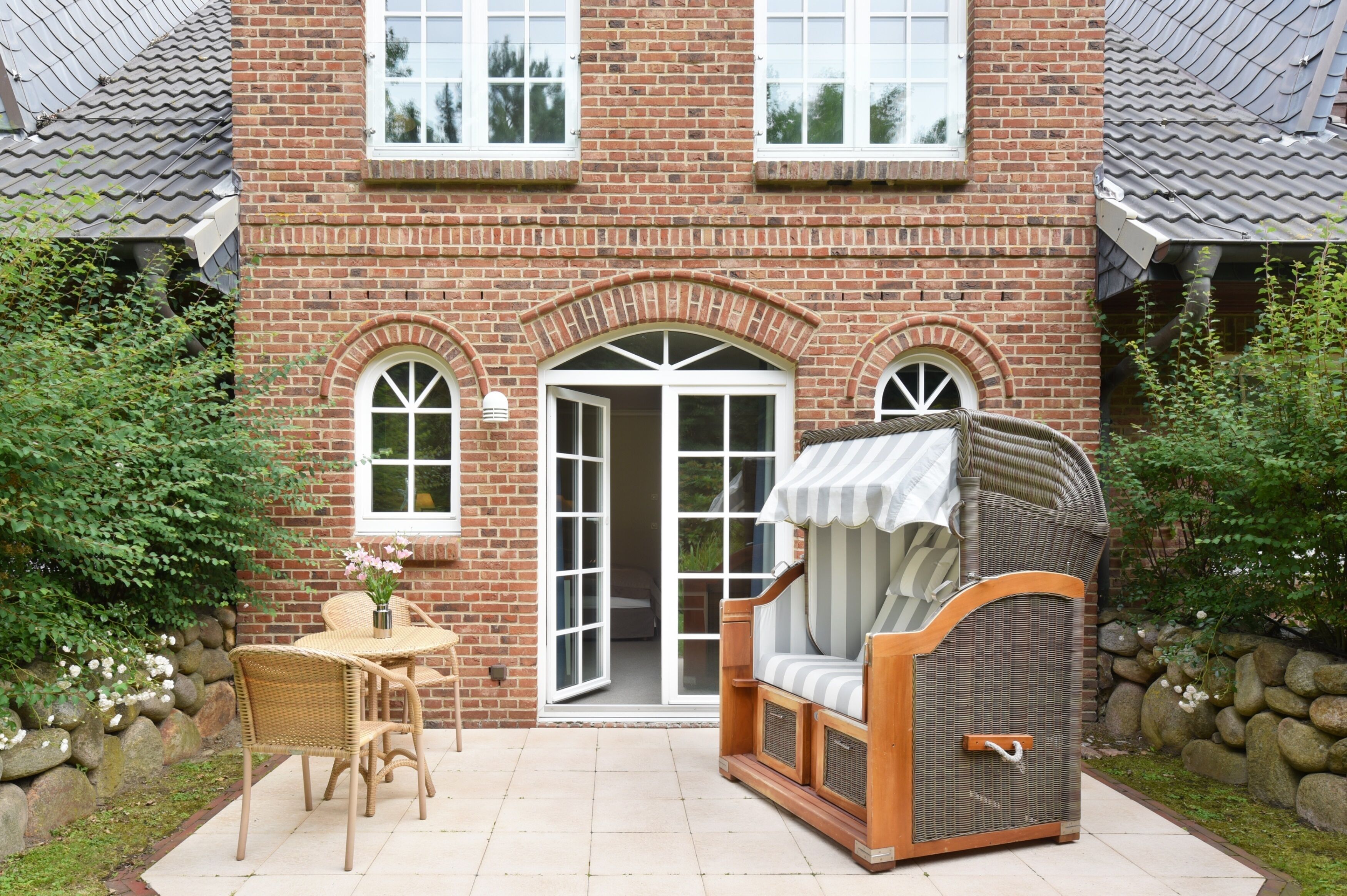 A brick house with a patio, a covered seating area, and a table with chairs.