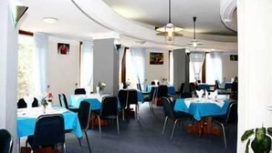 Ein Restaurant mit runden Tischen und Stühlen, weißen Wänden und einer Decke mit Einbauten für Beleuchtung.