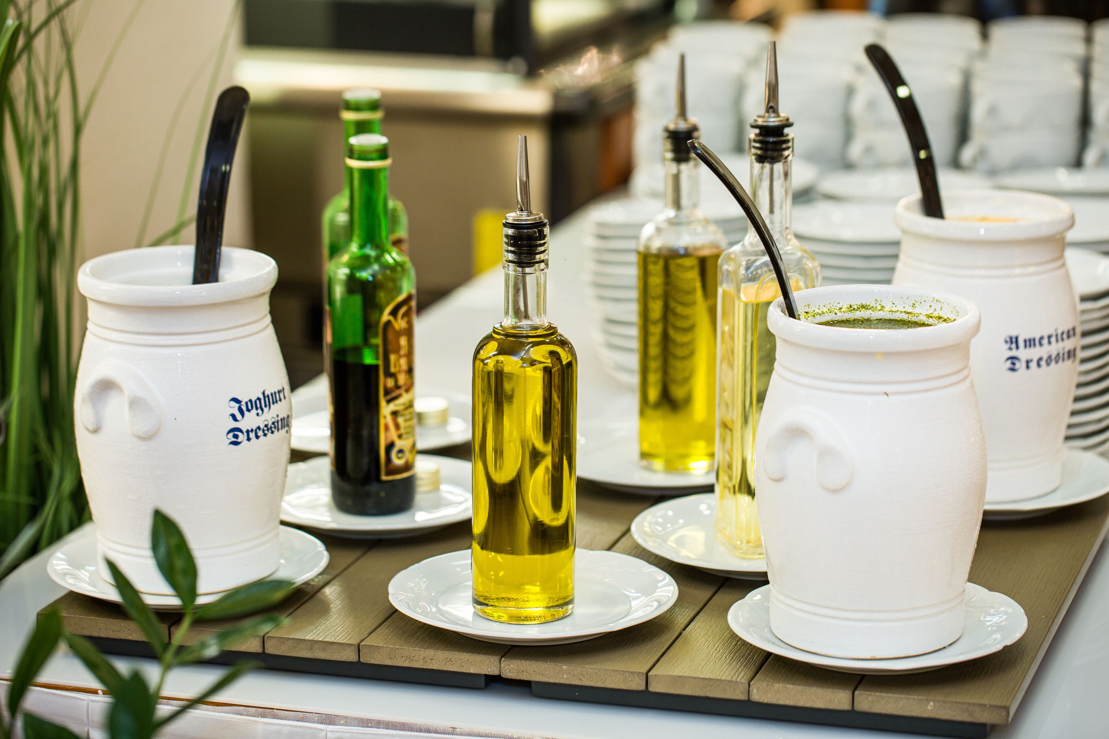 A table with various containers of condiments and oils, including a white jug labeled "Yoghurt Dressing".