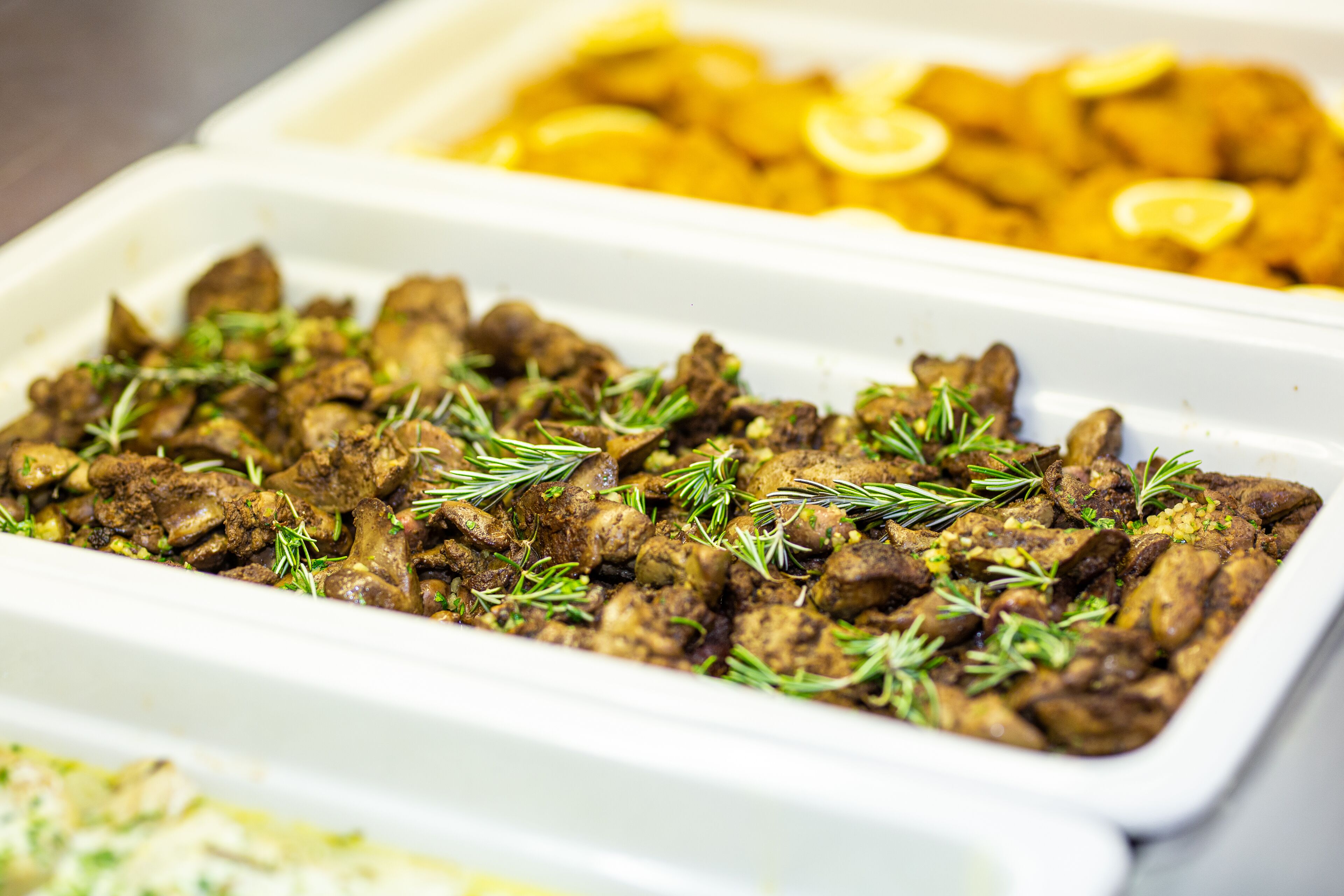 Een buffet met diverse gerechten, waaronder vlees en citroenpartjes.