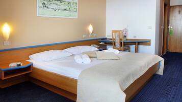 A neatly made bed with white linens, a wooden headboard, and a blue-striped wall.