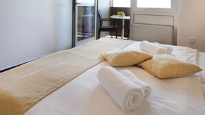 A hotel room with a bed, a woven mat, and a view of the outside. - Hotel Drazica (Krk)