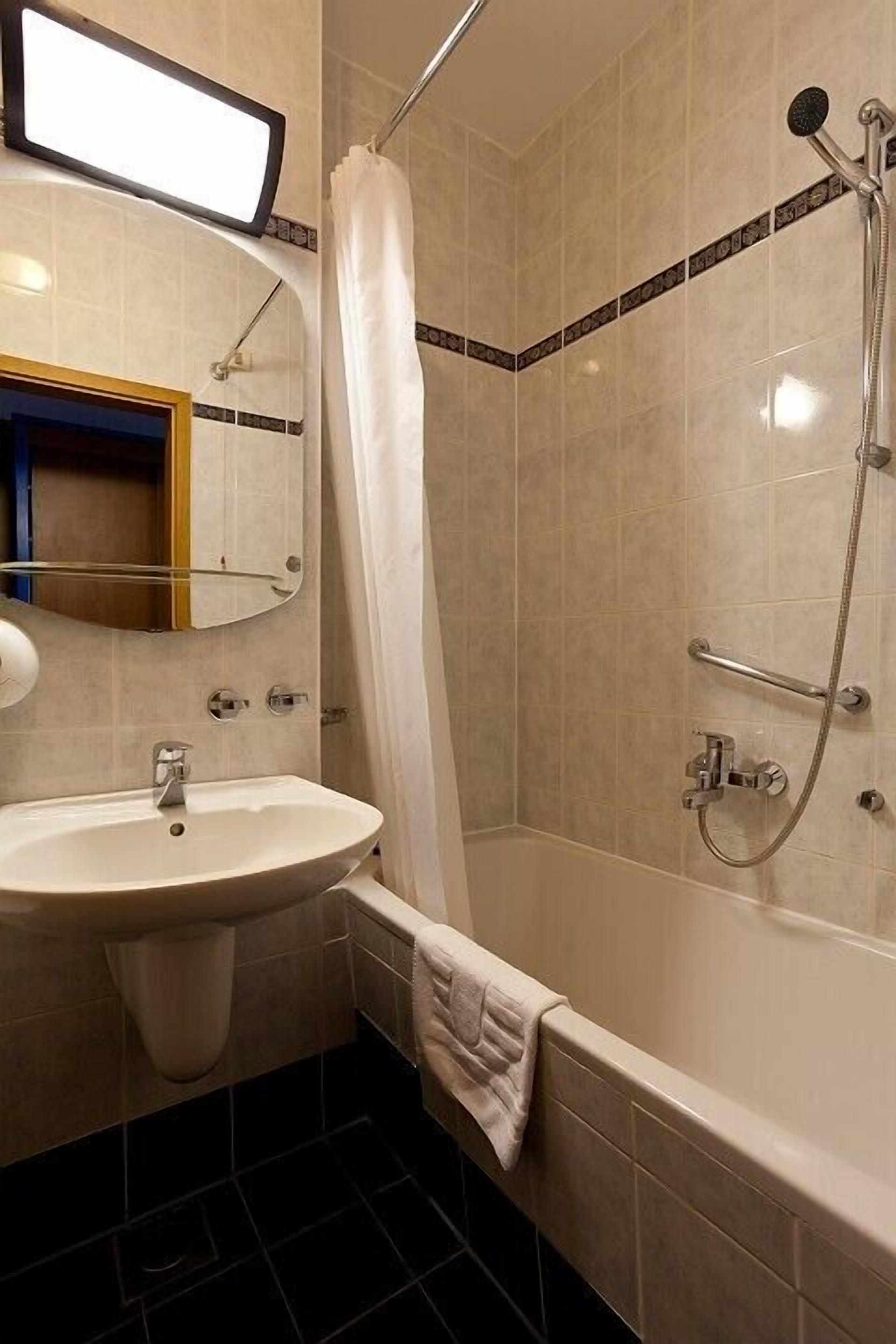 Une salle de bain équipée d’un lavabo, d’un miroir, d’une douche et d’un porte-serviettes.