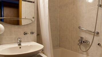 Une salle de bain équipée d’un lavabo, d’un miroir, d’une douche et d’un porte-serviettes.