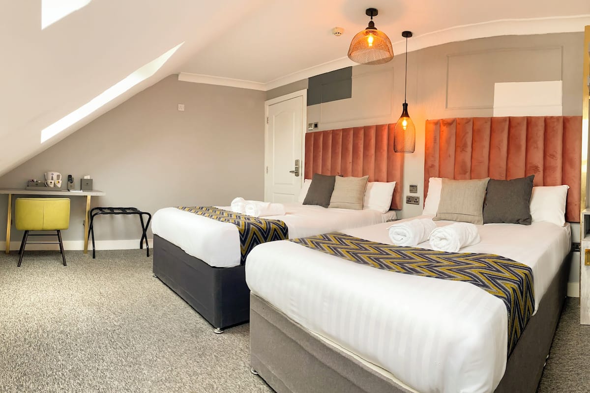Een hotelkamer met twee bedden, een bureau en een stoel.