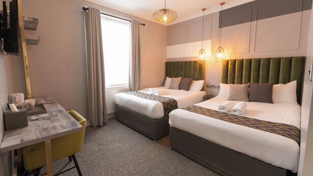 Habitación de hotel con dos camas, un escritorio, una silla, un televisor y una ventana con cortinas.