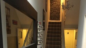 Una escalera con alfombra estampada, un candelabro y una estantería en la pared con libros.