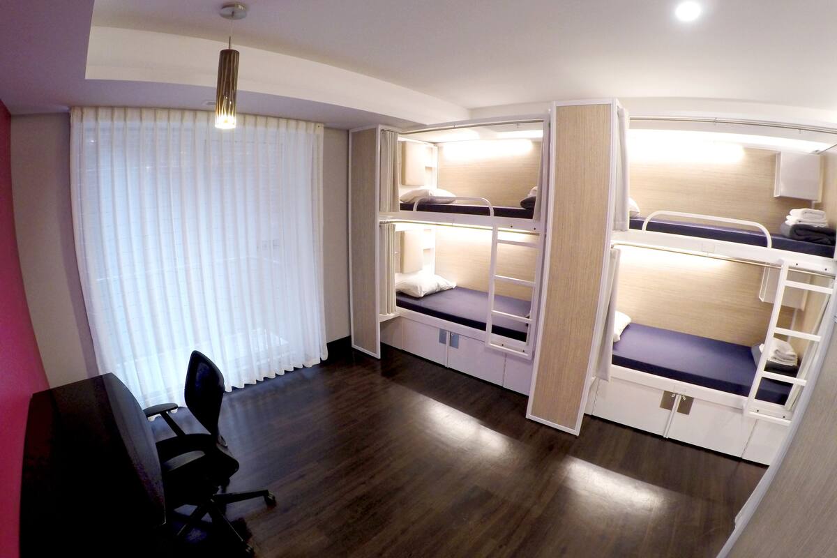 A compact room with bunk beds, a desk, and a chair.