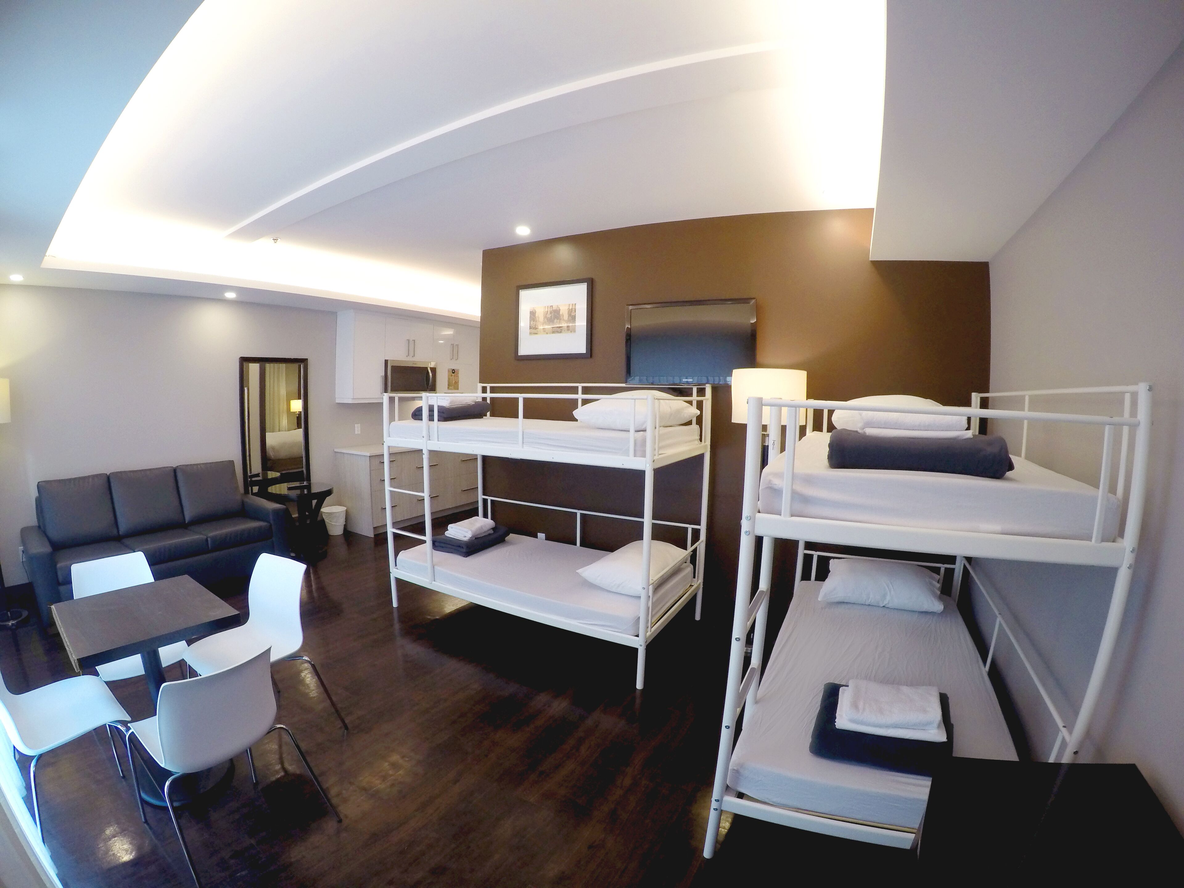 A hotel room with bunk beds, a sofa, a dining table, and a TV.