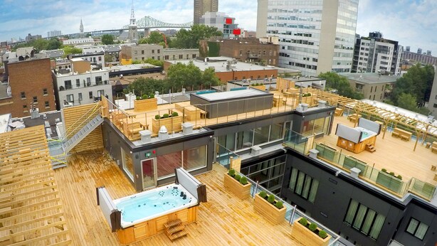 Eine Dachterrasse mit Whirlpool, Holzboden und Sitzgelegenheit im Freien.
