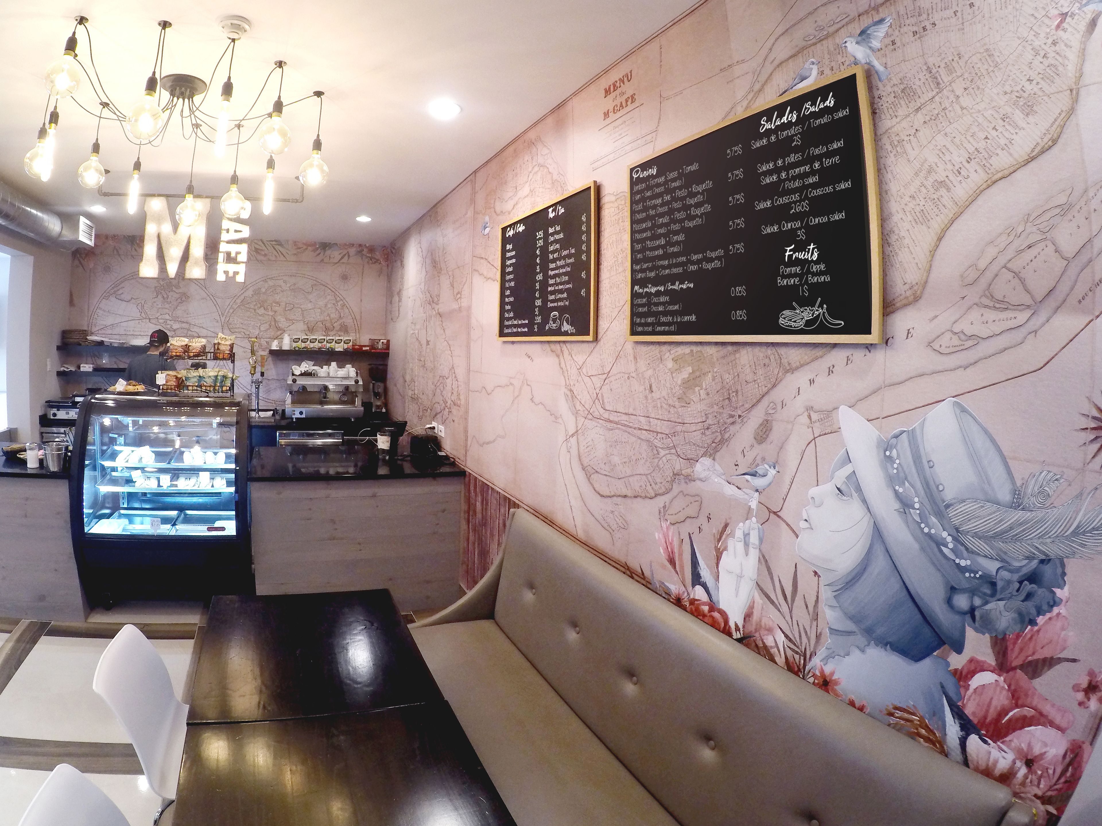 L’intérieur d’un café, avec un mur en marbre, un tableau affichant le menu, un espace pour s’asseoir et une vitrine.