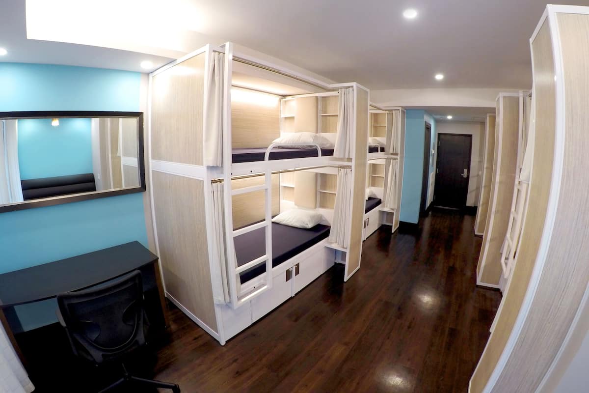 A bunk room with three bunk beds, a desk with a chair, and a large mirror on the wall.