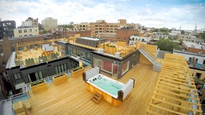 Eine Dachterrasse mit Whirlpool, Holzdeck und Glasgeländern.