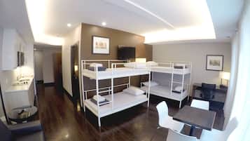 A bunk bed room with a desk, chair, and a TV on the wall.
