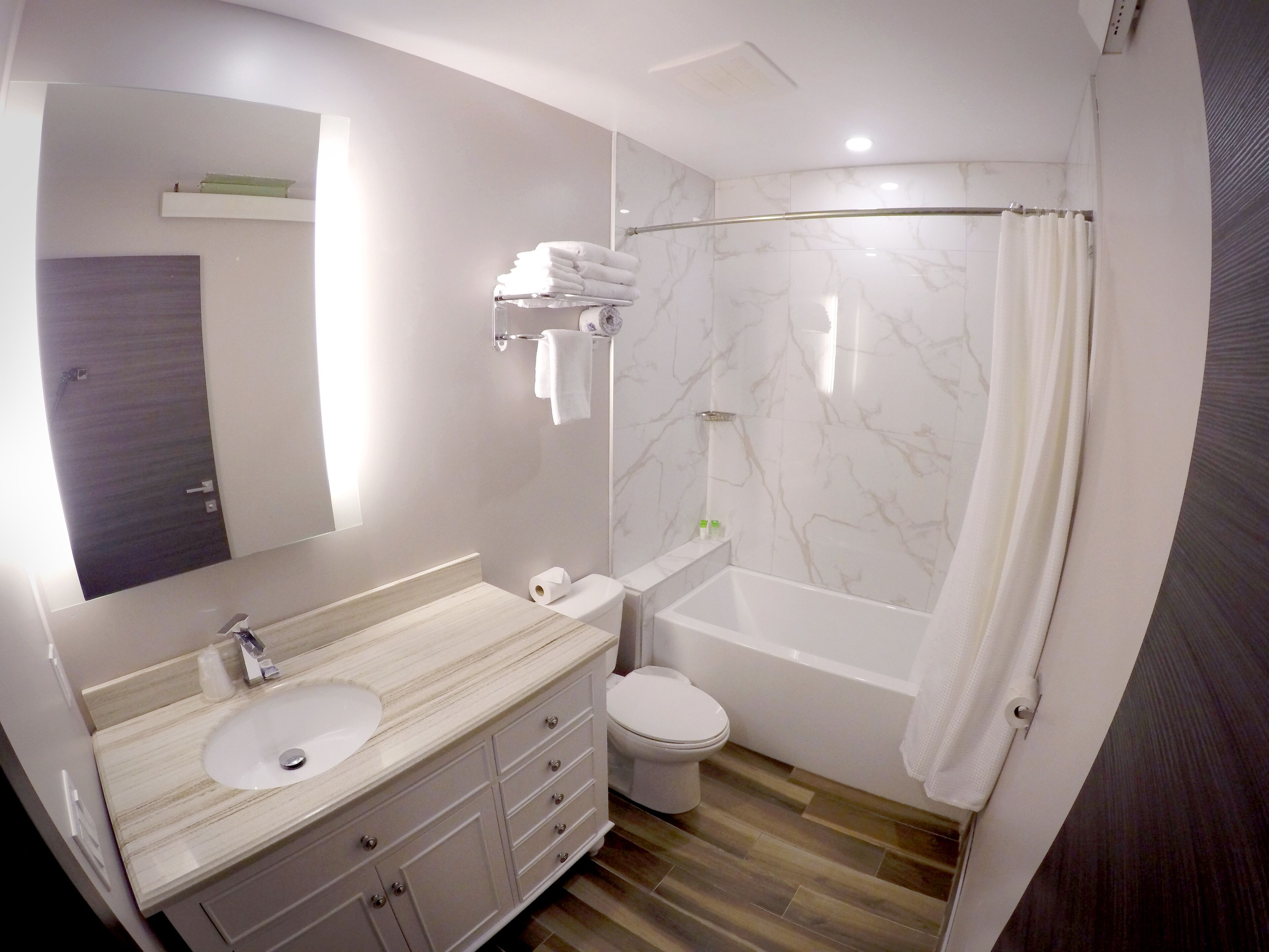 A modern bathroom with a marble vanity, a toilet, and a bathtub.