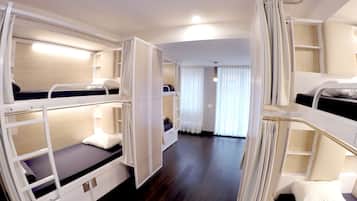 A hotel room with bunk beds, a wooden floor, and a view of the hallway.