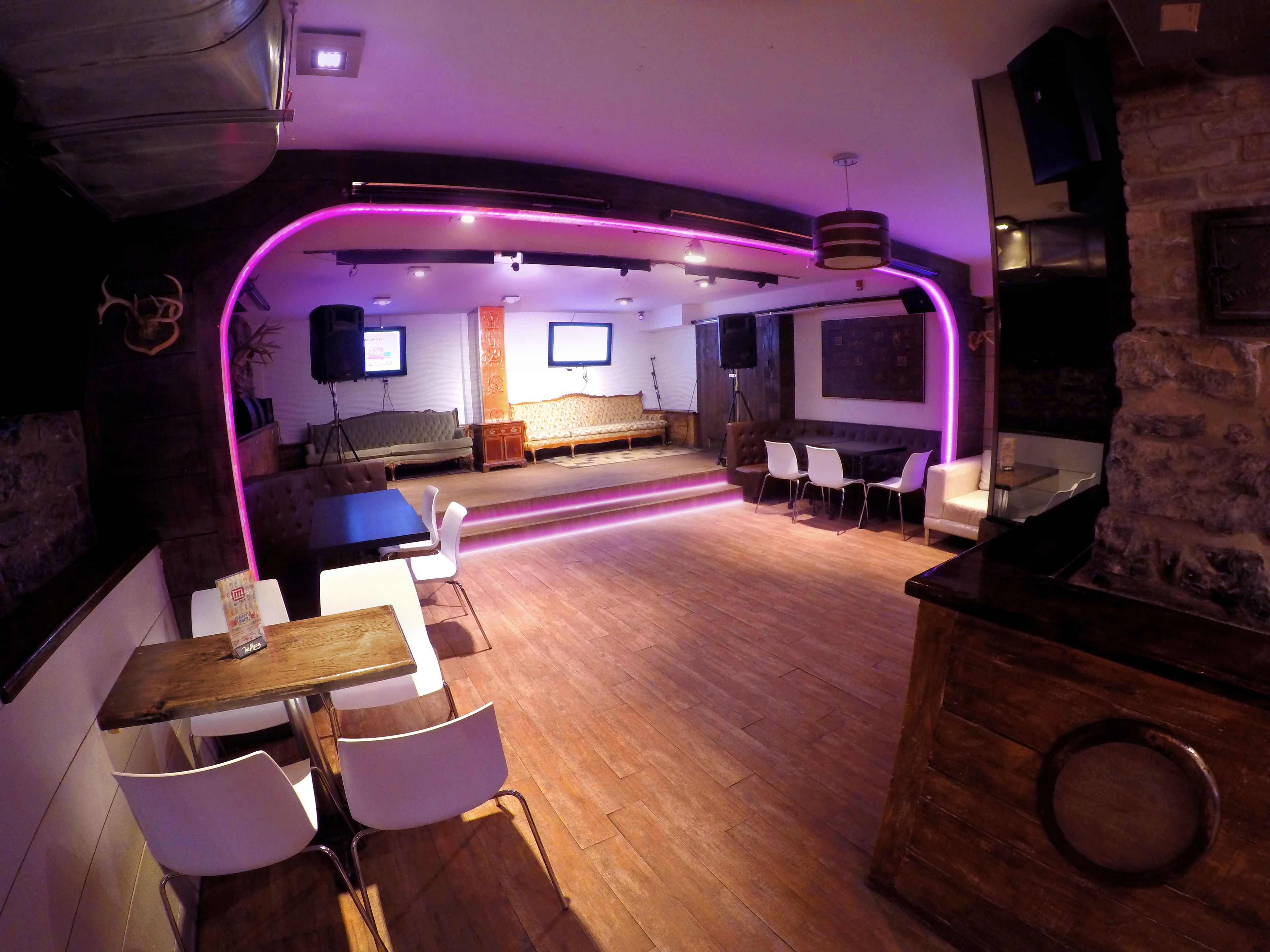 A modern interior with a bar area, seating, and a stage.