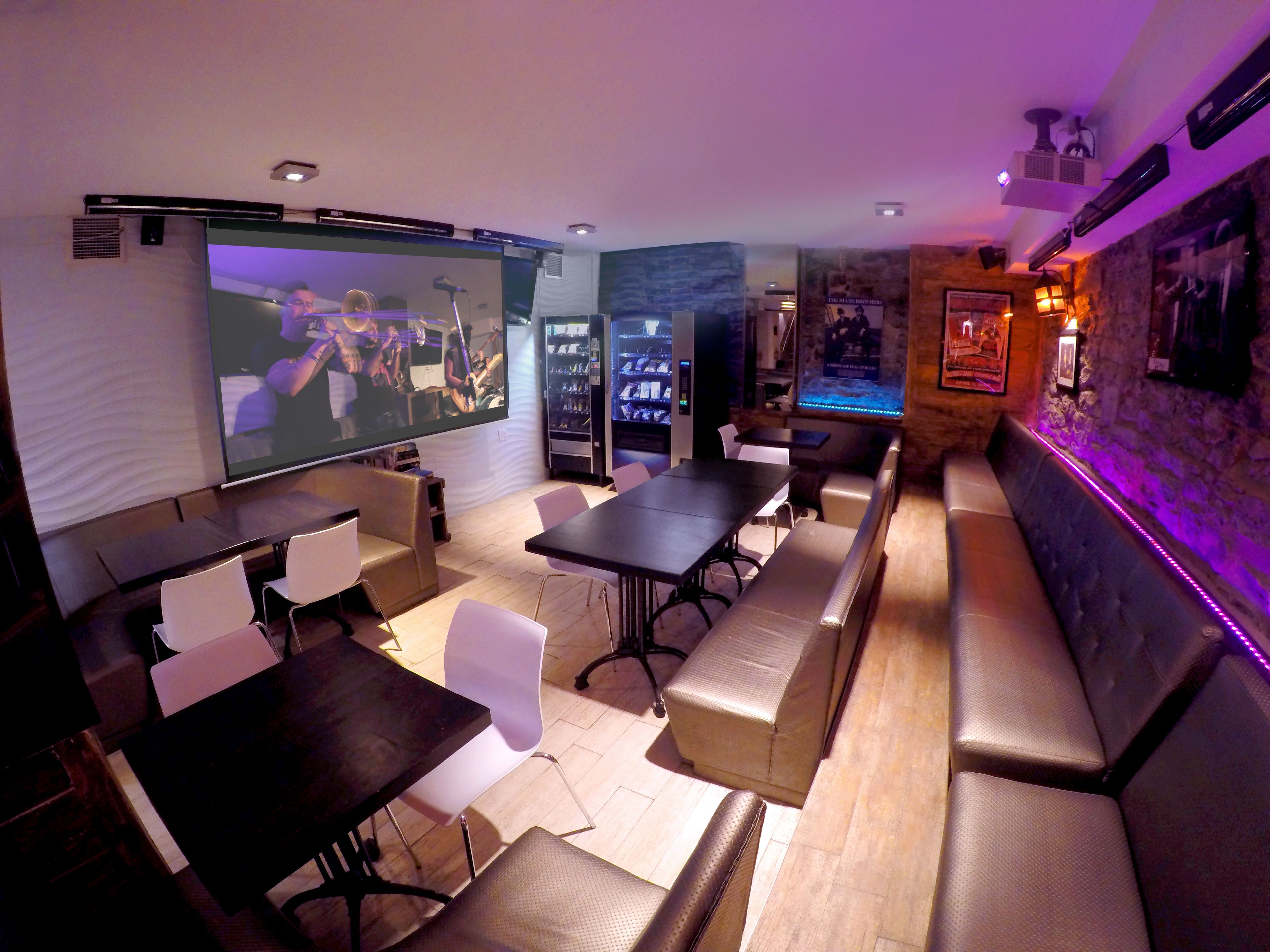 A room with a large screen, seating, and a bar area.