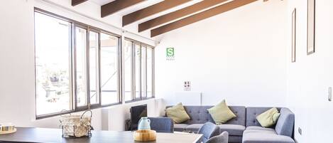 A modern interior with a dining area, a sofa, and a large window.