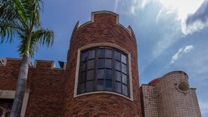 Un edificio con fachada de ladrillo, una entrada central con puerta de madera oscura y una ventana circular sobre la puerta.