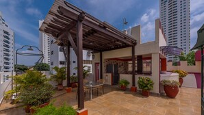 Terraza en la azotea con pérgola, mobiliario exterior y plantas en macetas.