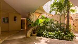 Un espacio interior amplio con techo curvo, una escalera y diversas plantas tropicales.