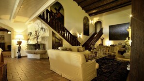 A spacious living room with a high wooden staircase, a large sofa, a coffee table, and a patterned rug. - Tenuta San Francesco (Trinitapoli)