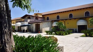 A courtyard with a yellow building, stone walls, and potted plants. - Tenuta San Francesco (Trinitapoli)