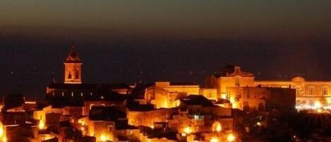 Vista nocturna de una ciudad con edificios iluminados y una imponente torre del reloj.