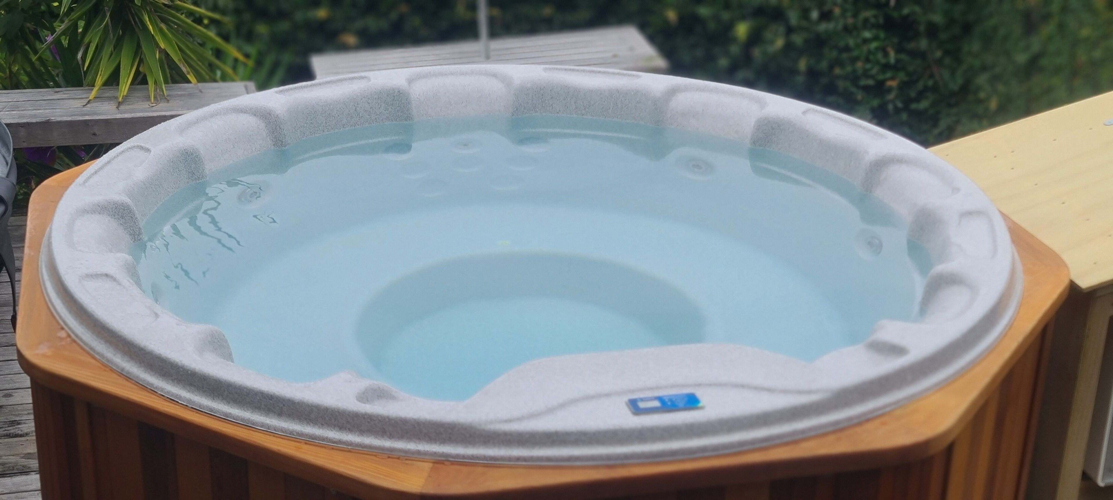 A hot tub on a wooden deck with a clear view of the surrounding greenery.