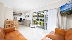 A modern apartment with a kitchen, dining area, and a balcony with a scenic view. - The Captains Motel (Russell)