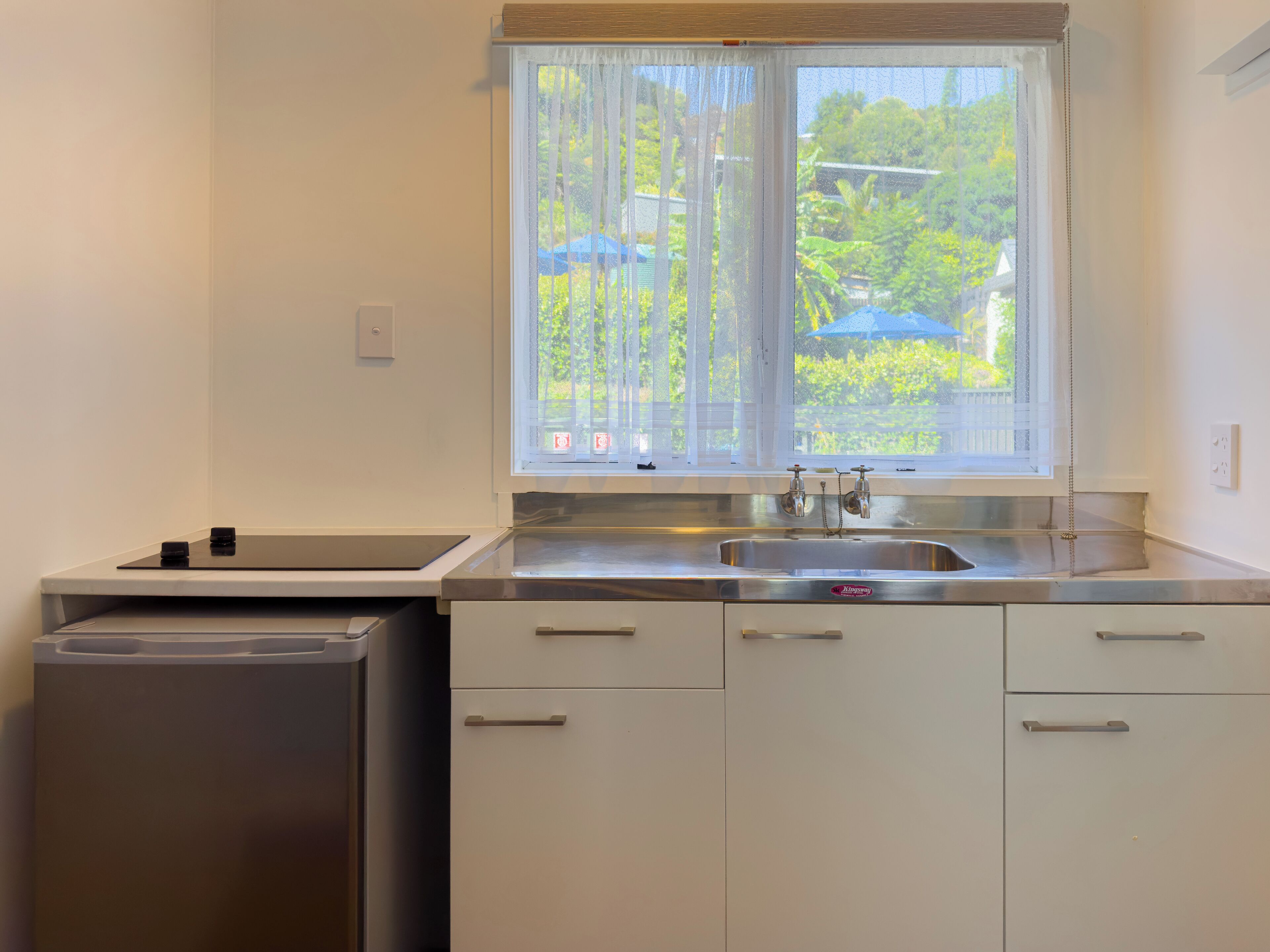 A compact kitchen with a stainless steel sink, a built-in dishwasher, and white cabinetry.