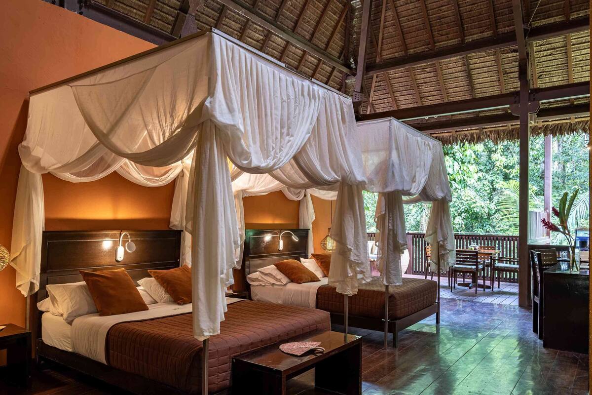 A room with two beds, each with a canopy, and a small table.
