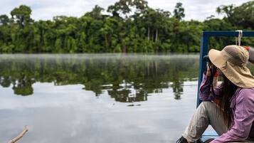 A person sitting on a blue wooden dock, wearing a hat and looking at the water.
