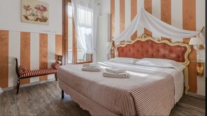 A hotel room with a bed, a chair, a bedside table, and a window with curtains. - Giulietta e Romeo (Verona)
