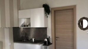 A compact kitchen with white cabinets, a dark countertop, and a wooden door. - Giulietta e Romeo (Verona)