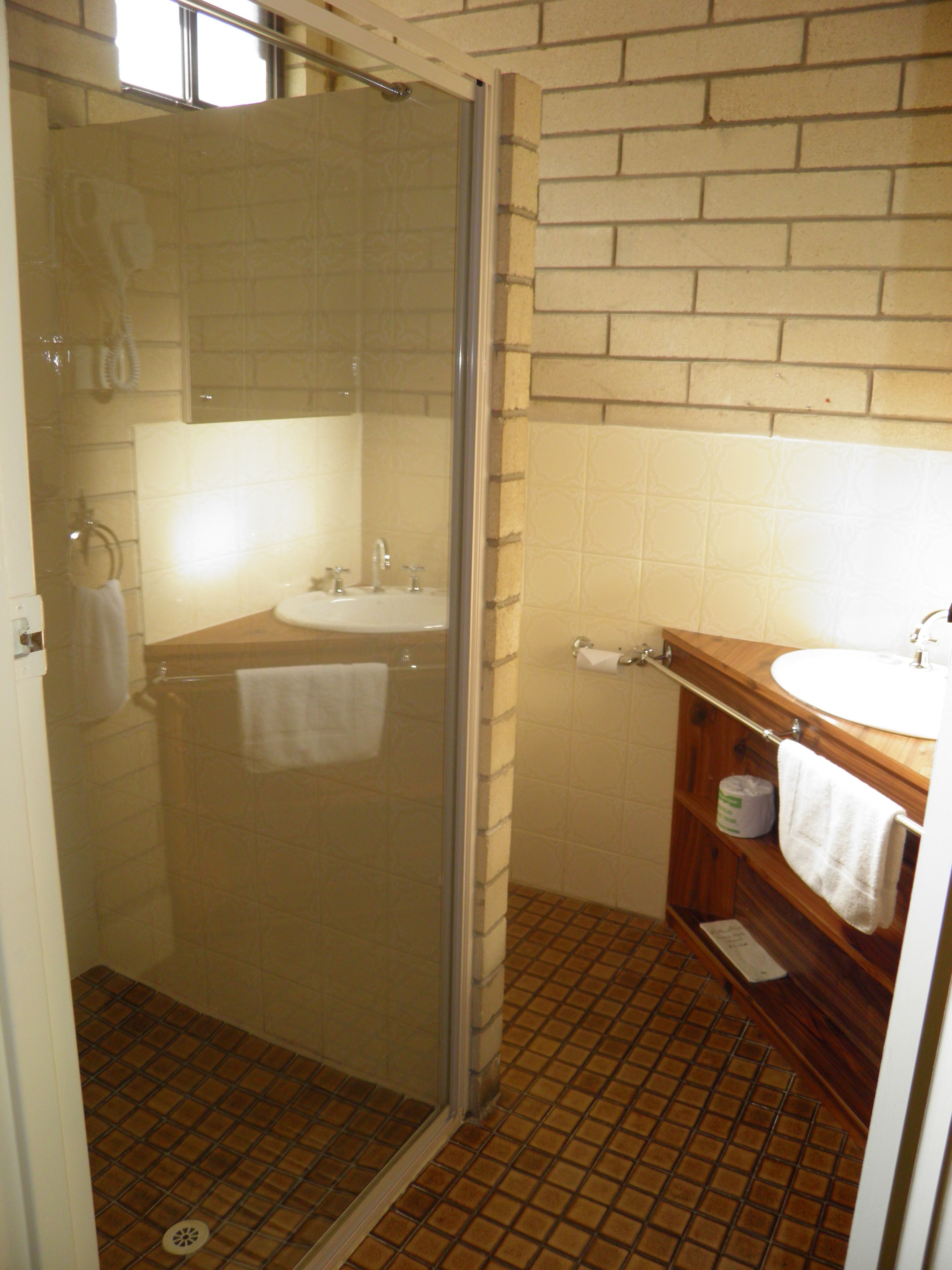 A bathroom with a glass shower enclosure, a sink, and a wooden vanity.