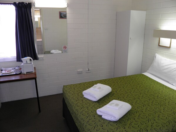 A hotel room with a bed, a desk with a coffee maker, a mirror, and a 'no smoking' sign on the wall. - 7th Street Motel (Mildura)