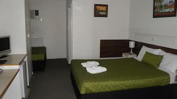 A hotel room with a bed, a desk with a computer, a TV, and a painting on the wall.