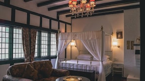 Una camera tradizionale con letto a baldacchino, un divano, un tavolino e una finestra con tende.