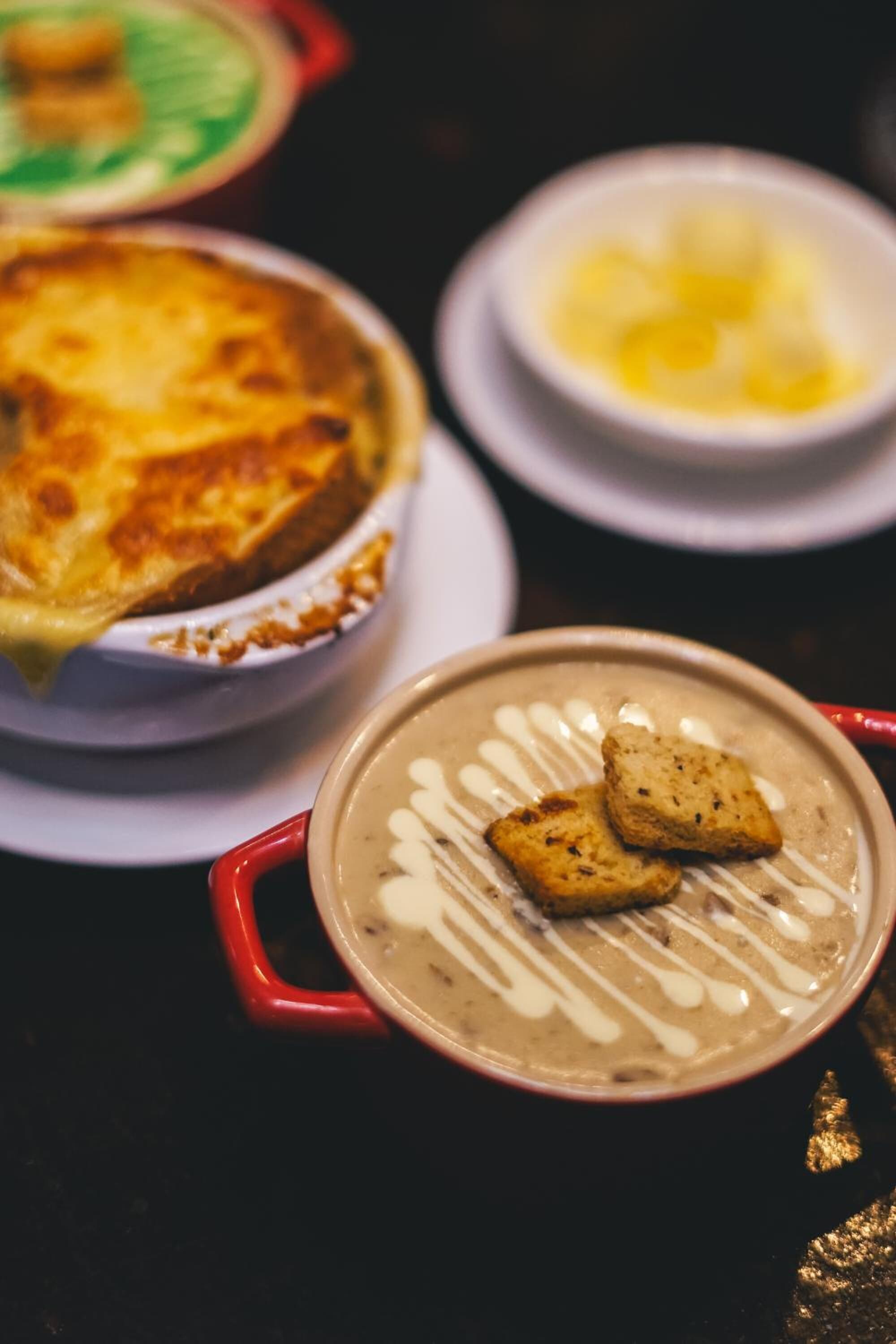 A table with a pie, a bowl of soup, and a plate with biscuits.