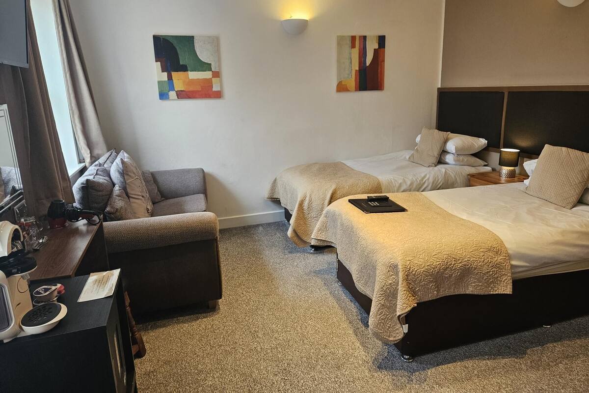 Ein Hotelzimmer mit zwei Betten, einem Schreibtisch mit Lampe und Bildern an den Wänden.