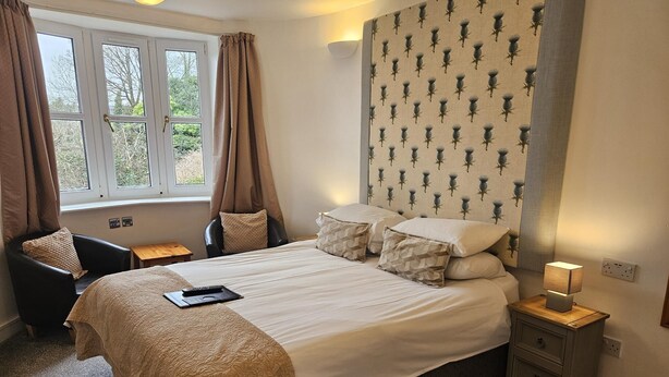 Een slaapkamer met een bed, een stoel, een nachtkastje en een raam met gordijnen.