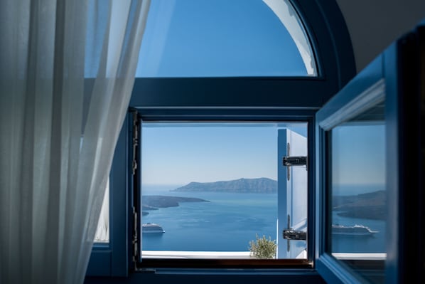 Una habitación con un amplio ventanal que ofrece vistas al mar y a la costa distante.