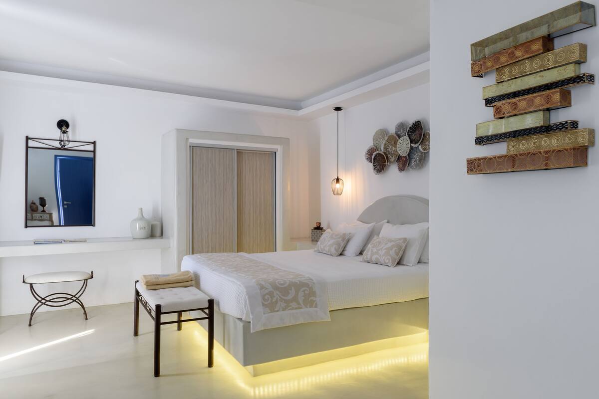 A modern bedroom with a bed, bedside table, chair, and decorative wall art.